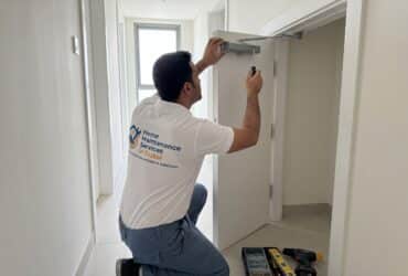 BHMS handyman installing a low profile door stopper on the floor in a Dubai apartment
