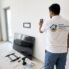 Handyman checking for wall studs before mounting a TV on a gypsum wall in a Dubai apartment