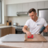 Kitchen wrapping Dubai cost - technician applying vinyl wrap to kitchen cabinets